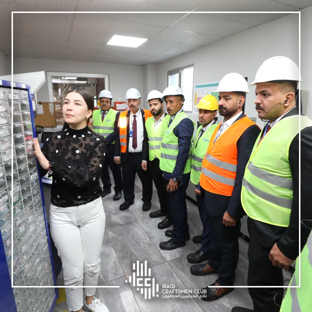 پیشەوەران بە کڵاوی سەلامەتییەوە لە ڕوونکردنەوەیەکی تەکنیکیدا لە ناو کارگە